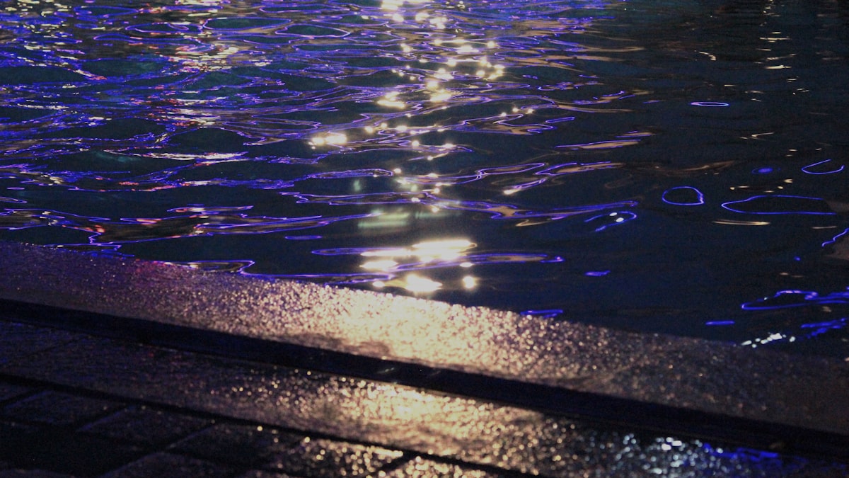 Piscina iluminada à noite com luzes LED refletindo na água